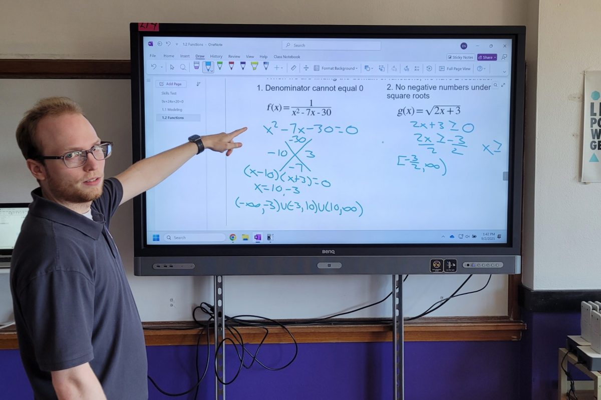 Mr. Natsis explains a math problem to students.